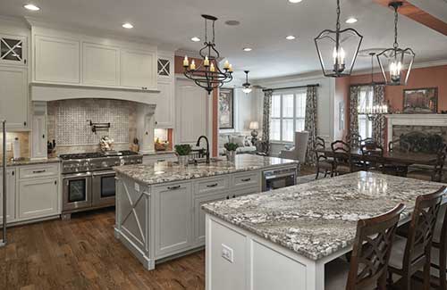 a large kitchen with grey marble countertops and rustic metal light fixtures